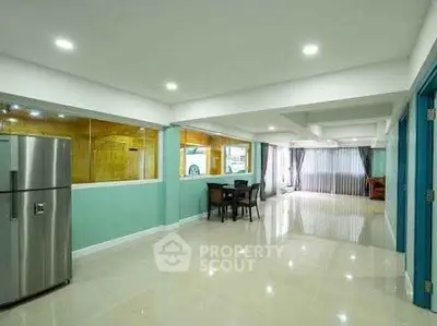 Spacious open-plan living area with modern kitchen and large windows.