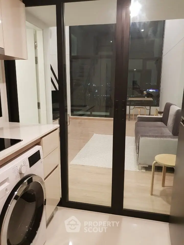 Modern apartment interior with washing machine and cozy living room view.