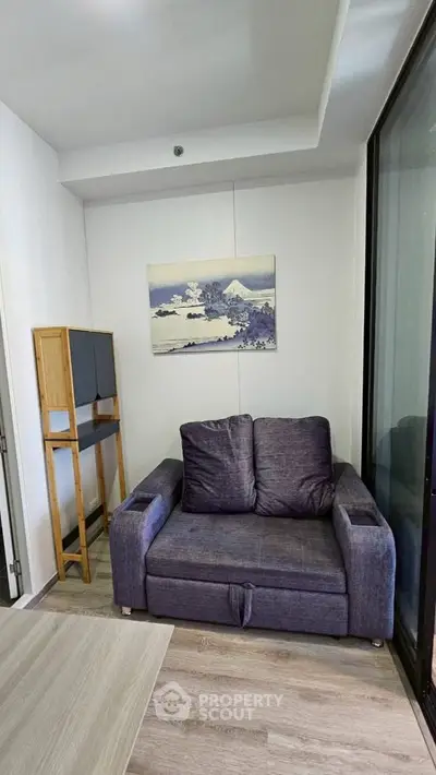 Cozy living room with modern sofa and artistic wall decor in a compact space.