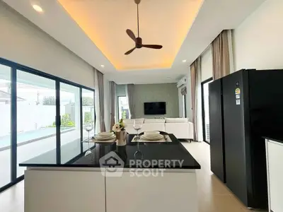 Modern open-plan kitchen and living room with sleek design and pool view, perfect for entertaining.