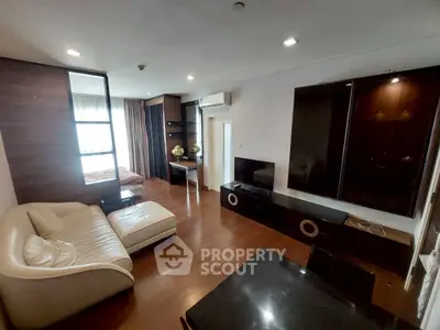 Spacious modern living room with elegant furniture and wooden flooring, featuring a cozy seating area and entertainment unit.