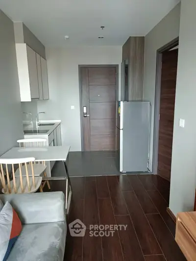 Modern apartment interior with sleek kitchen and cozy living area, featuring wooden flooring and contemporary design.