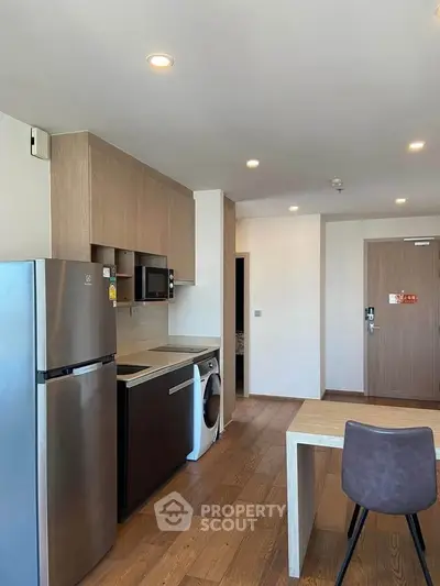 Modern kitchen with sleek appliances and wooden flooring in a stylish apartment.