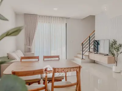 Modern living room with dining area and staircase, featuring sleek furniture and natural light.