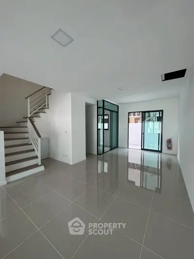 Spacious modern interior with glossy tiled floors and staircase, ideal for customization.