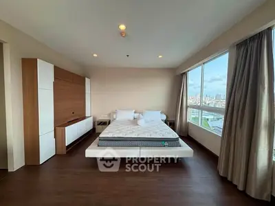 Spacious bedroom with large windows offering stunning city views, modern furnishings, and elegant decor.