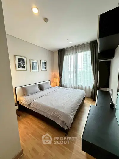 Modern bedroom with large window and stylish decor in a high-rise apartment.