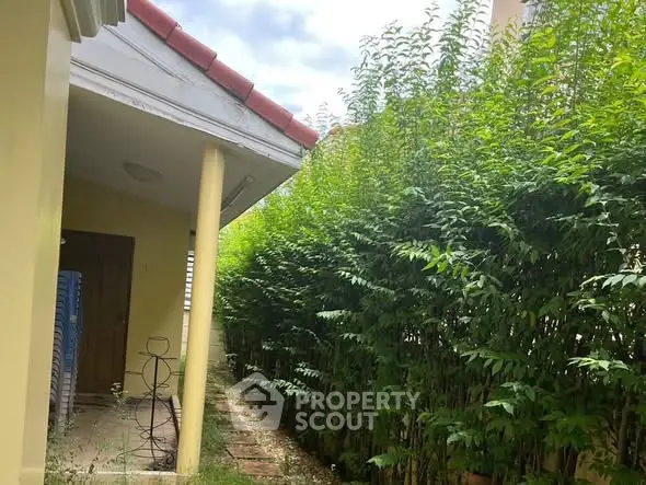 Charming garden pathway beside a cozy home with lush greenery and inviting entrance.