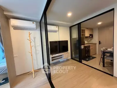 Modern apartment interior with glass partitions, featuring a cozy living area and compact kitchen.