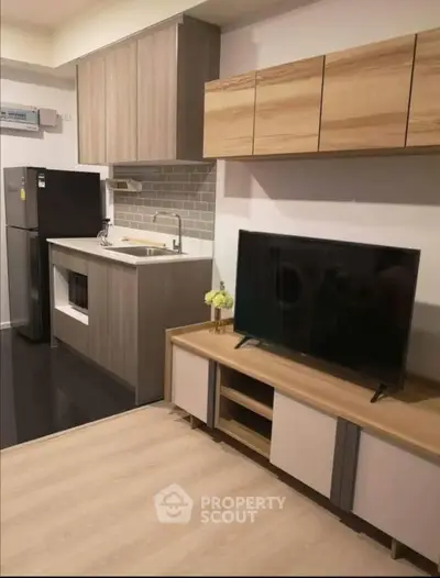 Modern kitchen and living area with sleek cabinets and appliances in stylish apartment.