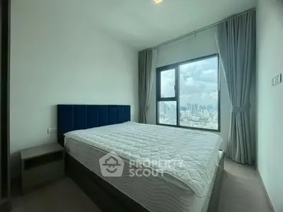 Modern bedroom with large window offering stunning city view and elegant furnishings.
