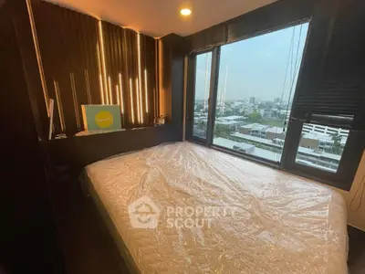Modern bedroom with large windows offering stunning city views, featuring a cozy bed and stylish decor.