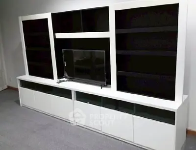 Modern living room with sleek white entertainment unit and flat-screen TV.