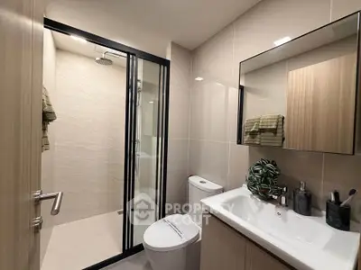 Modern bathroom with sleek fixtures and glass shower enclosure in a contemporary apartment.