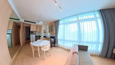 Spacious modern living room with open kitchen and large windows for natural light.