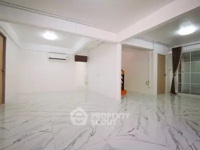 Spacious open-plan living area with marble flooring and modern lighting