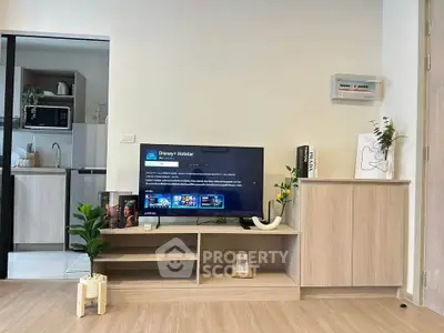 Modern living room with sleek TV setup and open kitchen layout, perfect for contemporary living.