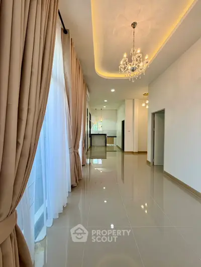 Elegant open layout with chandelier and floor-to-ceiling windows in modern home