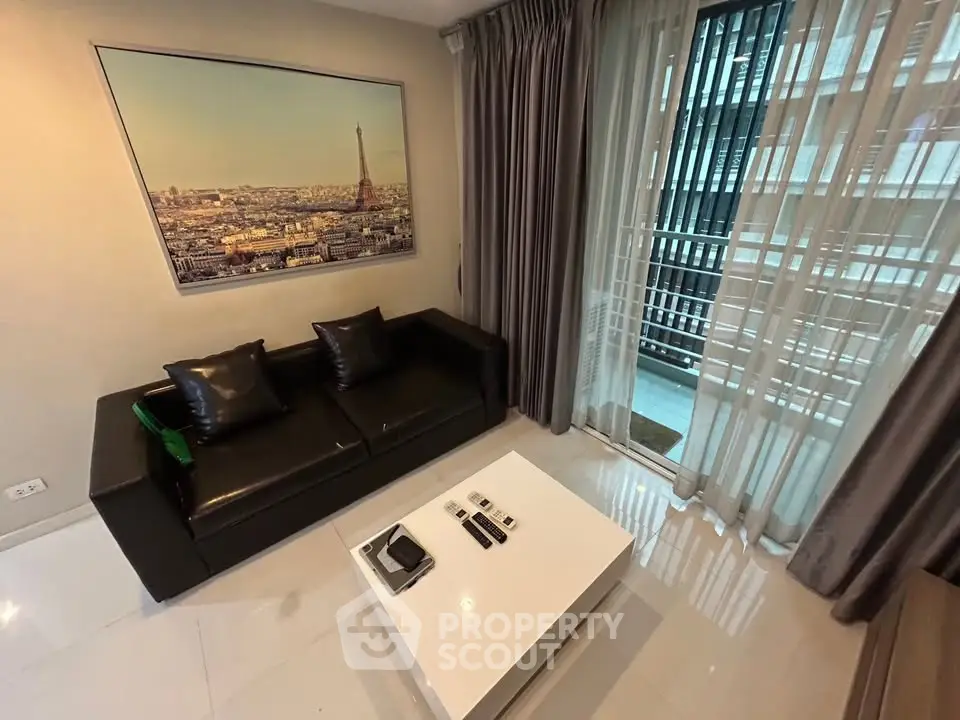 Modern living room with sleek black sofa and city view from balcony.