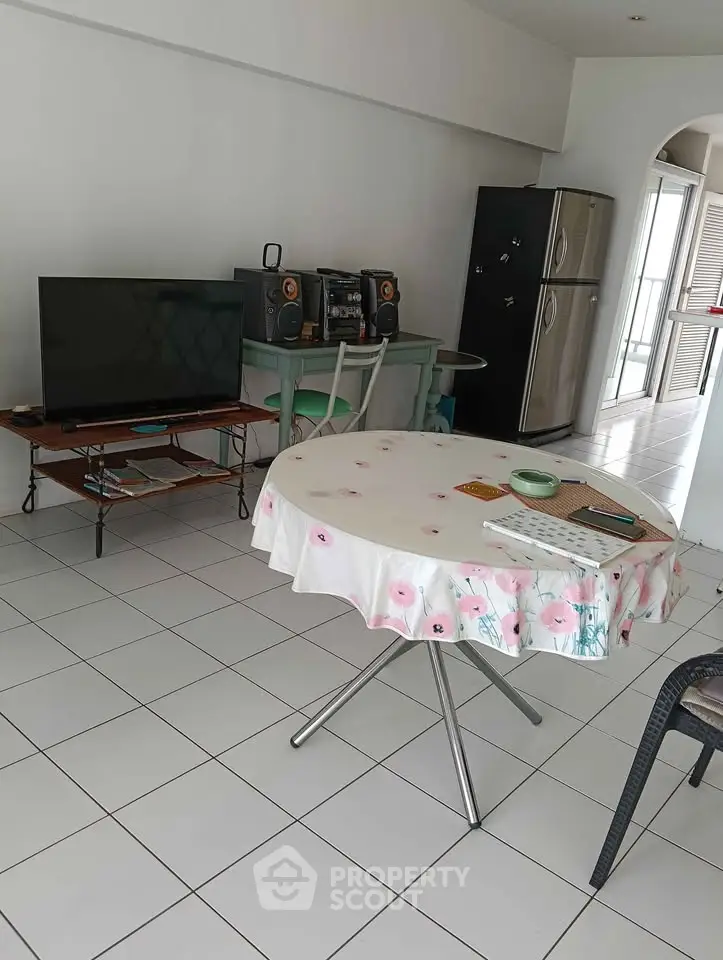 Cozy living room with tiled floor, TV, and dining table in modern apartment.