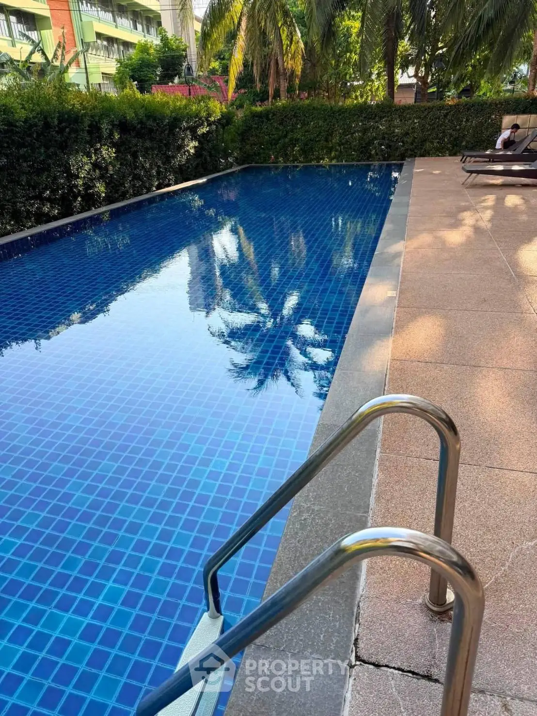 Luxurious outdoor swimming pool with lush greenery and sun loungers, perfect for relaxation and leisure.