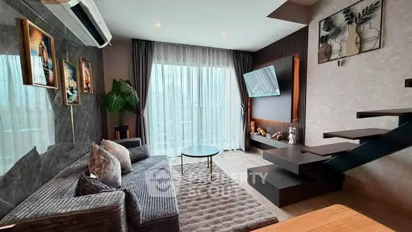 Modern living room with stylish decor, large windows, and unique staircase design.
