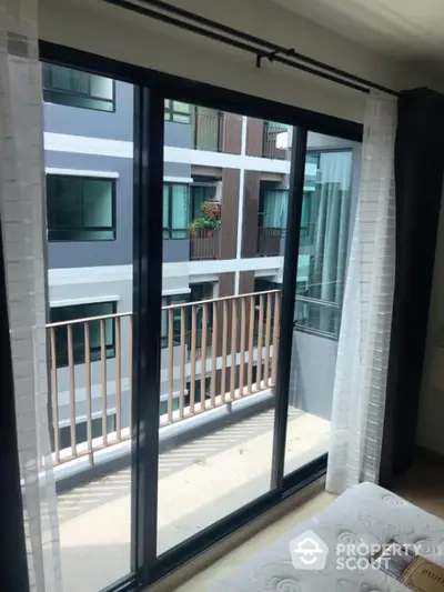 Modern apartment bedroom with balcony view and large sliding glass doors.