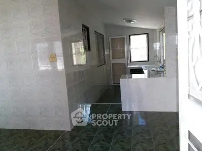 Spacious kitchen with tiled walls and floors, featuring ample natural light and modern fixtures.