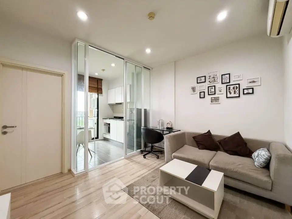 Modern living room with cozy sofa and stylish decor adjacent to a sleek kitchen.