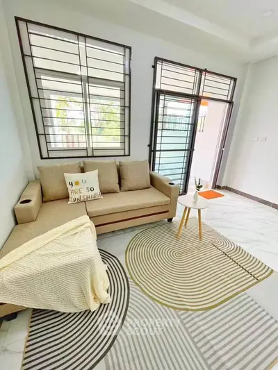 Bright living room with modern sofa and stylish rug, featuring large windows for natural light.