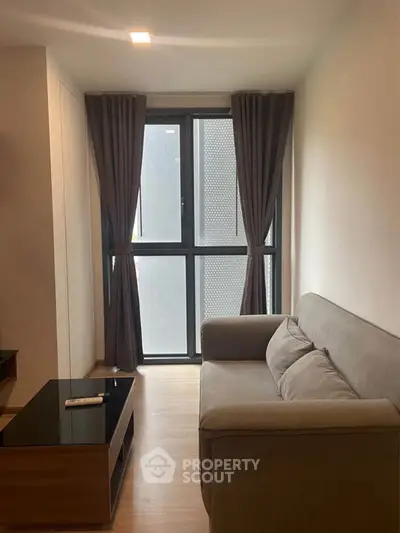 Cozy living room with modern sofa and large window, perfect for relaxation.