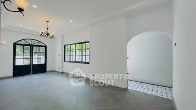 Spacious living room with elegant chandelier and large windows for natural light.