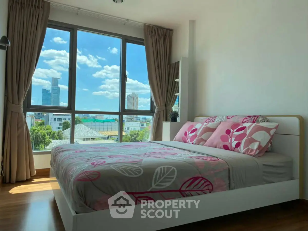 Bright bedroom with large window and city view, featuring modern decor and cozy ambiance.