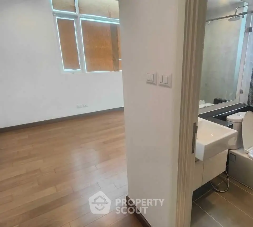 Modern apartment interior with wooden flooring and sleek bathroom design.