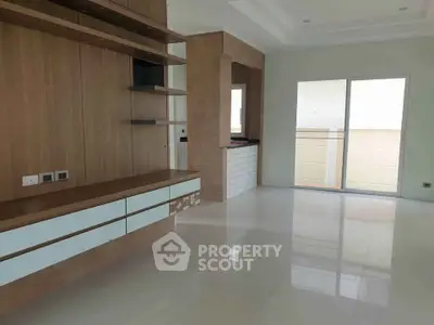 Spacious modern living room with sleek built-in shelving and large windows for natural light.