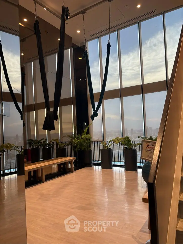 Spacious modern gym with aerial yoga setup and panoramic city views