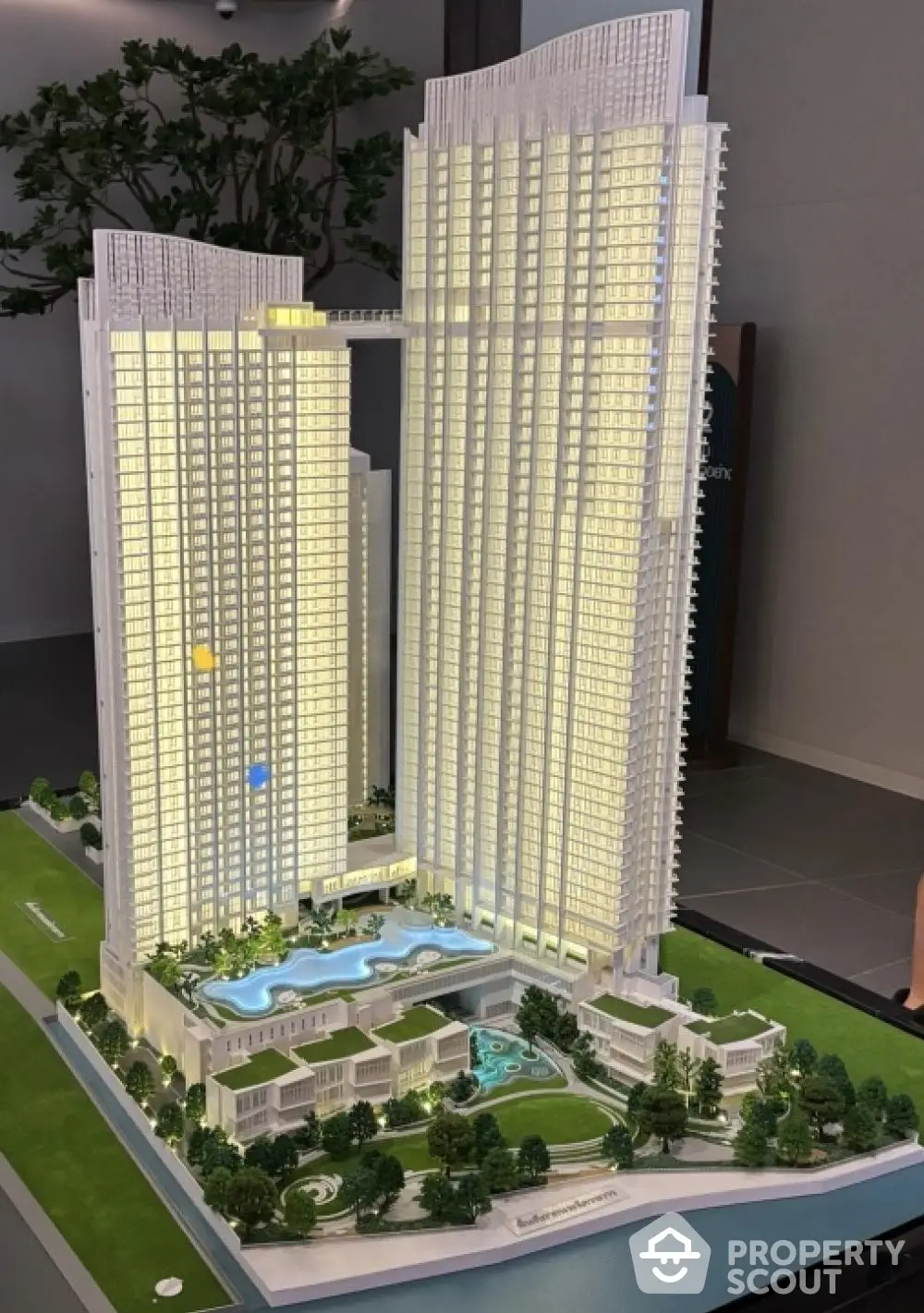 Architectural model of a modern high-rise residential complex with detailed landscaping, showcasing pools, green spaces, and a luxurious urban living experience.