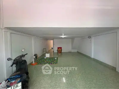 Spacious garage with tiled floor and scooter, ideal for storage or parking.