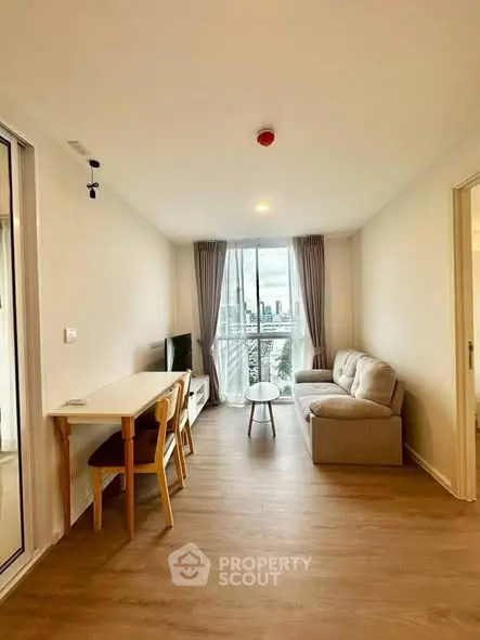 Modern living room with city view, cozy sofa, and dining area in a bright apartment.