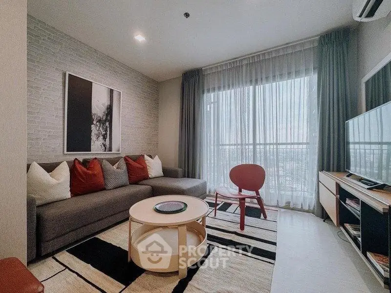 Modern living room with stylish decor and large window offering natural light.