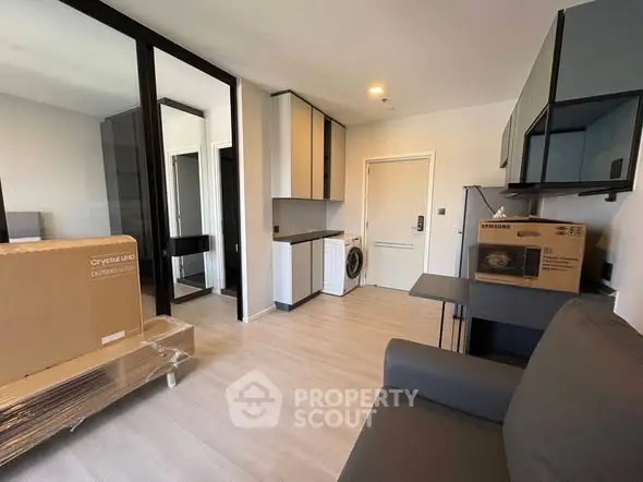 Modern apartment interior with compact kitchen and living area, featuring sleek cabinetry and new appliances.