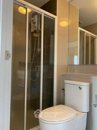 Modern bathroom with sleek shower and toilet in contemporary apartment.