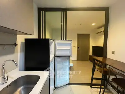 Modern kitchen with open fridge and sleek dining area in a stylish apartment.
