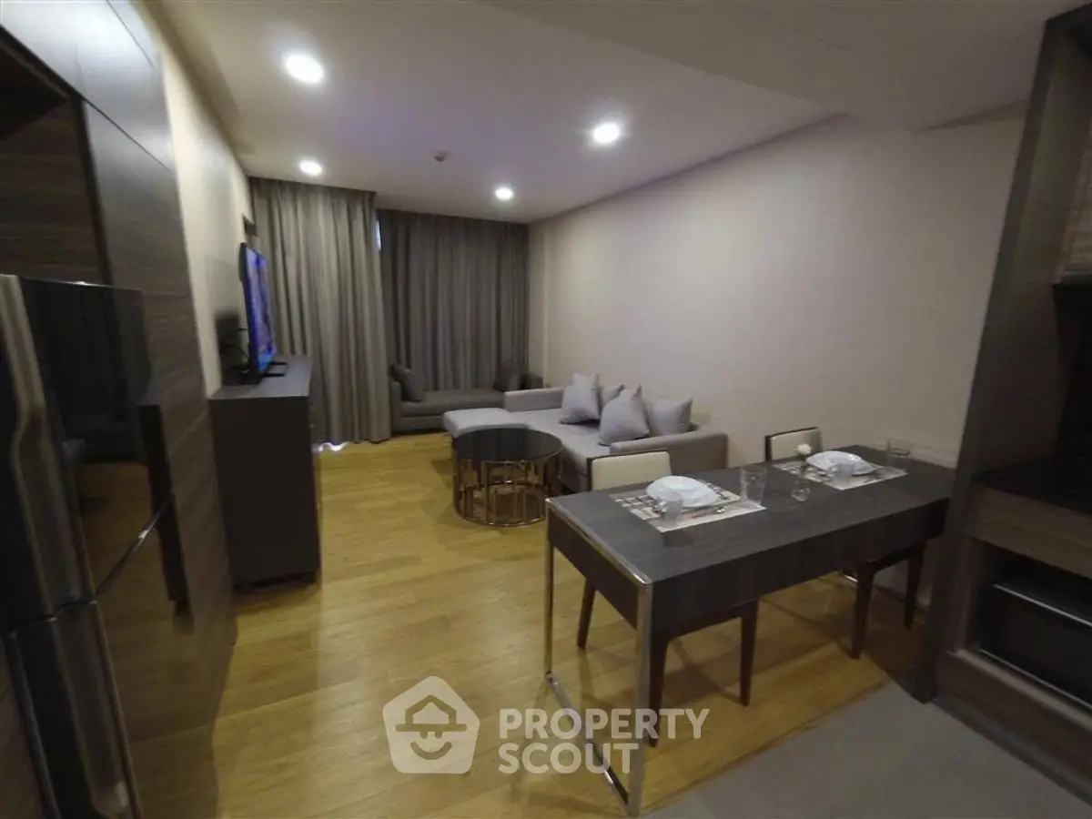 Modern living room with sleek furniture and dining area in open layout apartment.