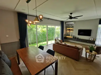 Spacious living room with modern decor and garden view, featuring elegant lighting and cozy seating.