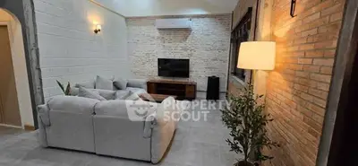 Modern living room with stylish brick walls and cozy gray sofa, featuring a sleek TV setup and ambient lighting.