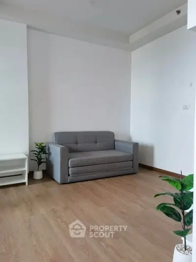 Minimalist living room with gray sofa and wooden flooring