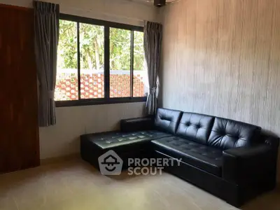 Cozy living room with black leather sectional sofa and large window view