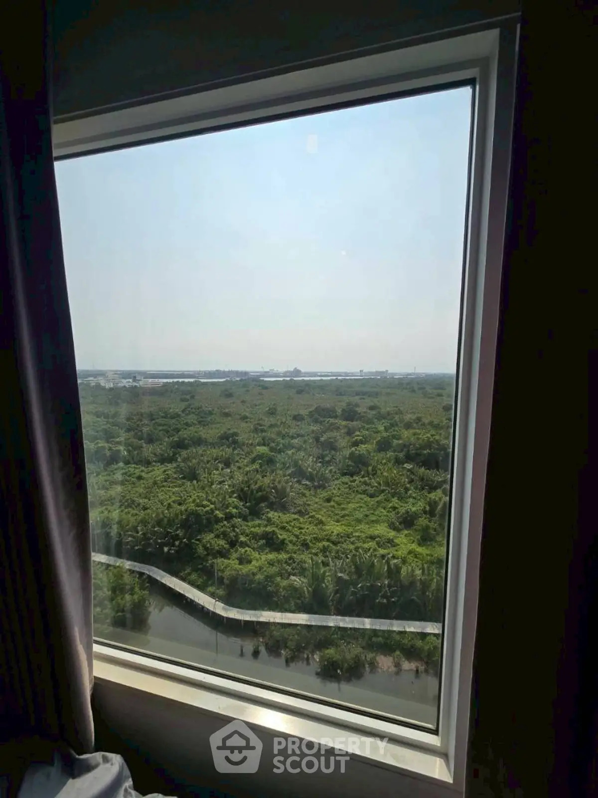 Stunning window view of lush greenery from a high-rise apartment, offering tranquility and natural beauty.