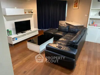 Spacious living room with sleek black leather sofa and modern entertainment center.
